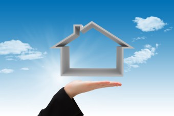 Composite image of hand carrying house with sky background